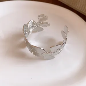 Detailansicht eines eleganten silbernen Blumen-Armreifs mit filigranen Blütenblättern.