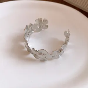 Detailansicht eines silbernen Metall-Armreifs im Vintage-Stil mit verbundenen Blumen.