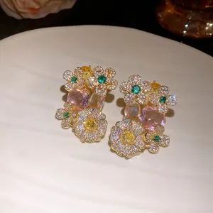 Détail de boucles d'oreilles en zircon floral avec des pierres roses et jaunes