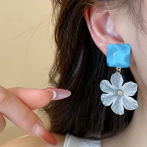 Macro di orecchini a perno quadrati in acrilico blu con ciondolo a fiore bianco elegante