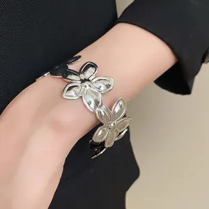 Detailansicht eines eleganten silbernen Blumenarmreifs aus Metall an einem weiblichen Handgelenk