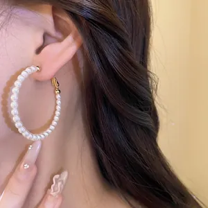Elegant French vintage style pearl hoop earring with gold-tone wire shown on an ear