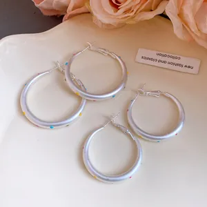 Detailed view of silver hoop earrings with colorful polka dots in two various sizes