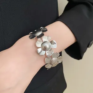 Detailansicht eines silberfarbenen Blumenarmbandes aus Metall am Handgelenk getragen