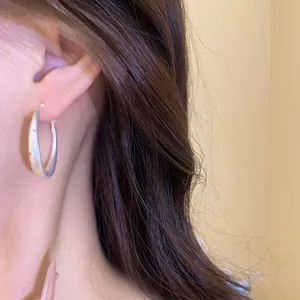 Close-up detail view of a stylish silver hoop earring with colorful polka dots worn by a model