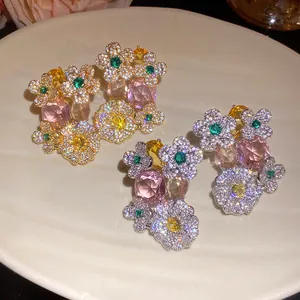 Détail de boucles d'oreilles fleurs en zircon avec pierres roses et jaunes sur plat