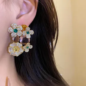 Détail de boucles d'oreilles fleuries en argent avec zircons de couleur sur modèle