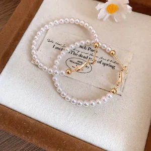 Detailed macro view of elegant pearl beaded hoop earrings with gold-toned metal clasp details.