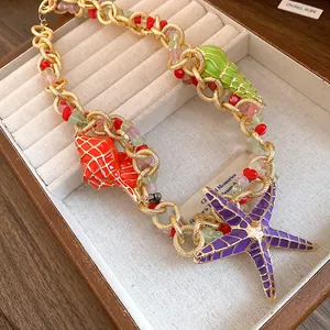 Detail of enamel starfish and conch charms on a beaded vintage gold necklace.