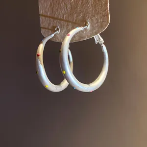 Detailed close-up of minimalist silver hoop earrings with vibrant colorful polka dots.