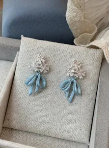 Detail view of light blue bow earrings featuring sparkling flower-shaped crystal studs