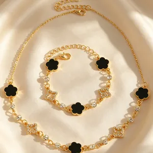 Vue détaillée de l'ensemble collier et bracelet doré avec trèfles noirs et étoiles