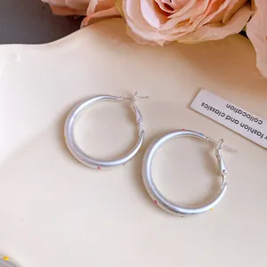 Macro detail of silver hoop earrings featuring vibrant multi-colored polka dot patterns