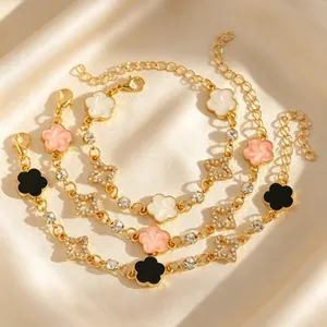 Gros plan de bracelets dorés avec fleurs en émail et pendentifs étoiles sur fond de satin.