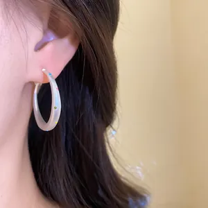 Detail view of stylish matte acrylic hoop earrings with colorful polka dots on ear