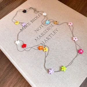 Long layered necklace with colorful flower beads displayed on a minimalist beige book