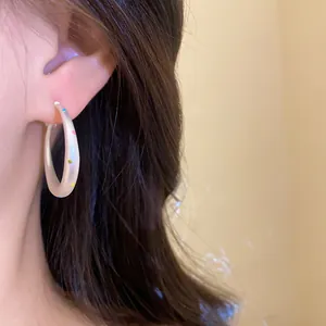 Close-up view of stylish white hoop earrings featuring vibrant colorful polka dots on a model