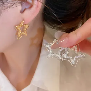 Macro shot of gold and silver textured hollow star earrings with elegant sparkly finish