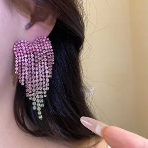 Detailed close-up of a sparkling pink rhinestone heart tassel earring worn on a model's ear