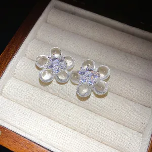 Close-up detail of elegant clear resin flower stud earrings with sparkling zircon centers