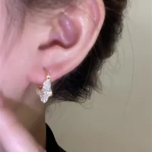 Detailed view of shimmering star-shaped zircon hoop earrings worn on an Asian female ear