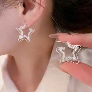 Macro view of hollow star-shaped stud earrings with a textured silver finish and silver needle