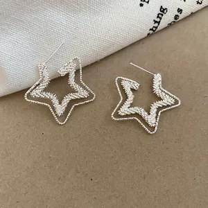 Detailed view of silver-toned star-shaped stud earrings with double-layered hollow texture