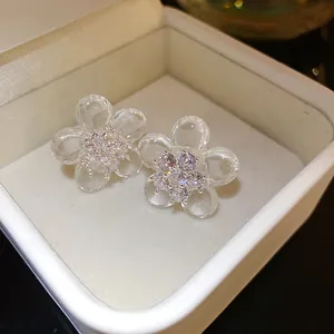 Detailed macro view of clear resin flower earrings featuring sparkling zircon stone centers