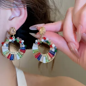Primo piano di orecchini a cerchio con perle di vetro colorate e strass champagne.
