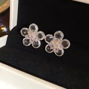 Macro view of clear resin flower stud earrings with sparkling zircon centers in a jewelry box