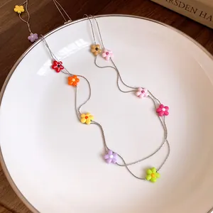 Close-up detail of colorful floral charms on a delicate double-strand silver necklace