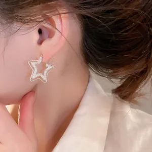 Detailed view of dainty sparkling 18k gold plated star earrings worn by an elegant model