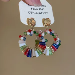 Primo piano di orecchini circolari colorati in vetro e strass su cartoncino OBN Jewelry