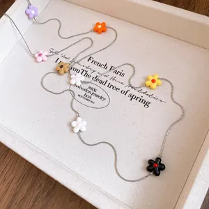 Detailed view of a long necklace featuring colorful flower charms in a white tray