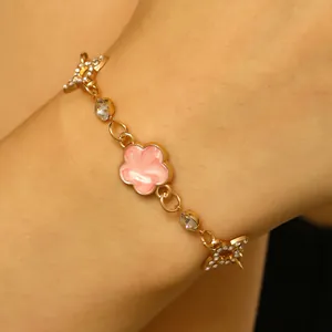 Vue détaillée du bracelet élégant avec fleur en émail rose et étoile en strass sur le poignet.