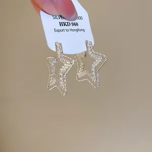 Close-up view of textured 18k gold plated star hoop earrings with sterling silver needle