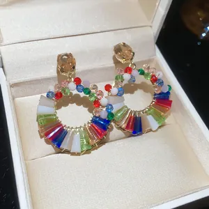 Primo piano di orecchini a cerchio in cristallo colorato in una scatola regalo bianca.