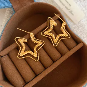 Detail of 18k gold plated double star earrings displayed in a brown jewelry box