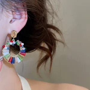 Primo piano di un orecchino a cerchio con perline colorate e cristalli su una modella.