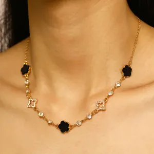 Détail d'un collier plaqué or avec des trèfles noirs et des pendentifs en forme d'étoile.