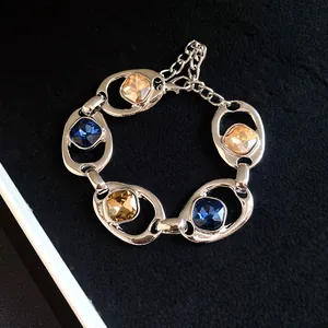 Détail d'un bracelet vintage à maillons ovales évidés avec cristaux bleus et champagne.