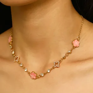 Détail d'un collier doré avec fleurs en émail rose et étoiles en cristal