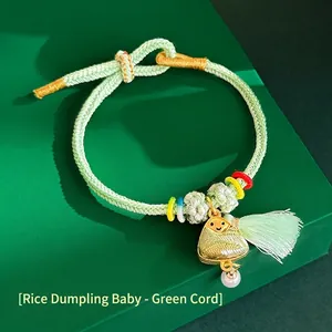 Close-up of a handwoven green silk bracelet featuring a Zongzi charm and tassel detail.