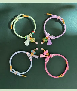 Detailed view of four colorful handmade woven bracelets with Song Jin triangle charms and tassels