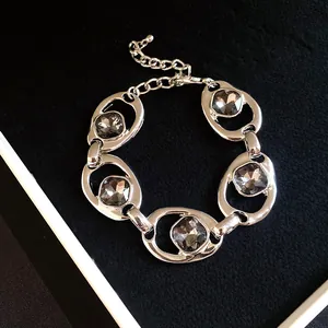 Détail d'un bracelet vintage argenté avec des maillons ovales et des cristaux gris