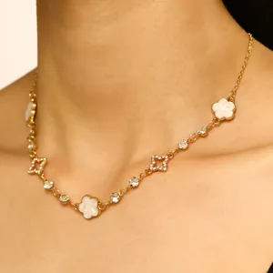 Gros plan détaillé d'un collier en or avec trèfles en émail blanc et pendentifs étoiles