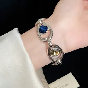 Gros plan d'un bracelet à maillons ovales en argent avec cristaux bleus et jaunes