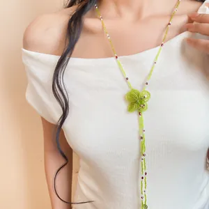 Close-up of an elegant green crystal beaded necklace featuring a woven flower pendant on a model