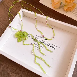 Detailed close-up of handmade green crystal beaded necklace with floral pendant charm