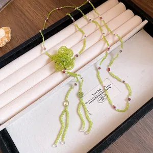 Detailed view of handmade green beaded necklace with intricate flower pendant design.
